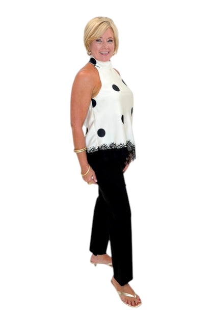 Side view of woman wearing Swagger Boutique’s Cream Polka Dot Asymmetrical Halter Neck Satin Lace Top by Entro with jeans against white studio background.