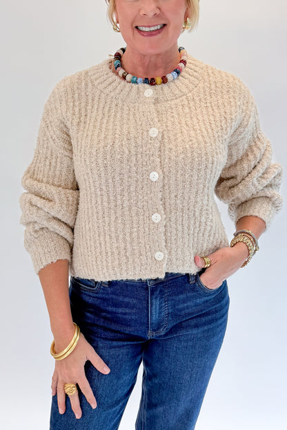 Front detail view of woman wearing Swagger Boutique’s Cream Ribbed Button Up Cardigan with jeans against white studio background.