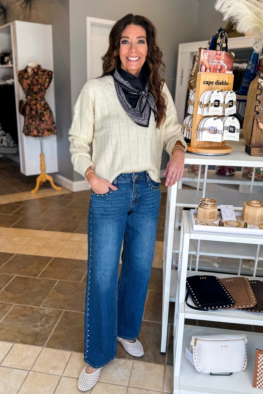 Front view of woman wearing Swagger Boutique’s Cream Ribbed Textured Sweater with jeans standing at the store.