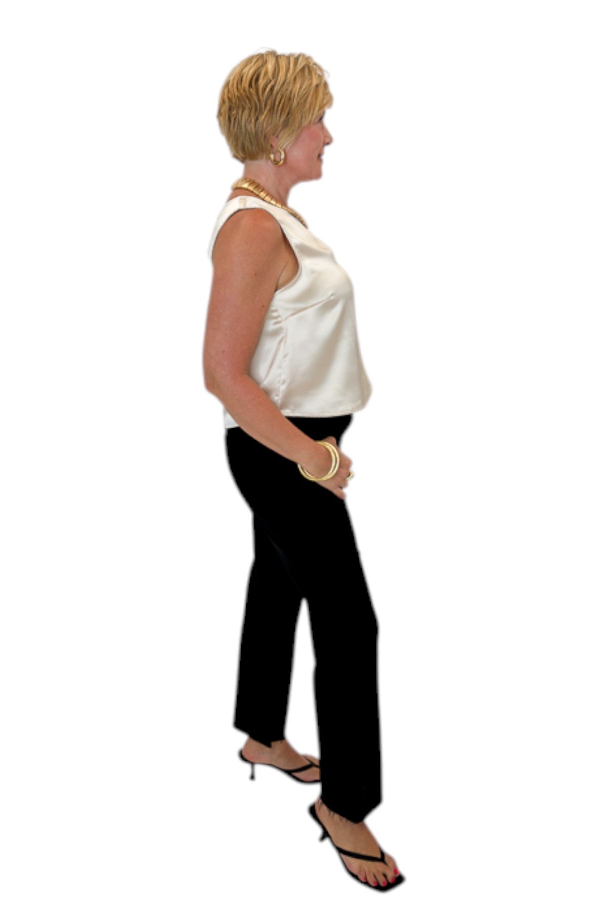 Side view of woman wearing Swagger Boutique’s cream satin tank with jeans against white studio background.
