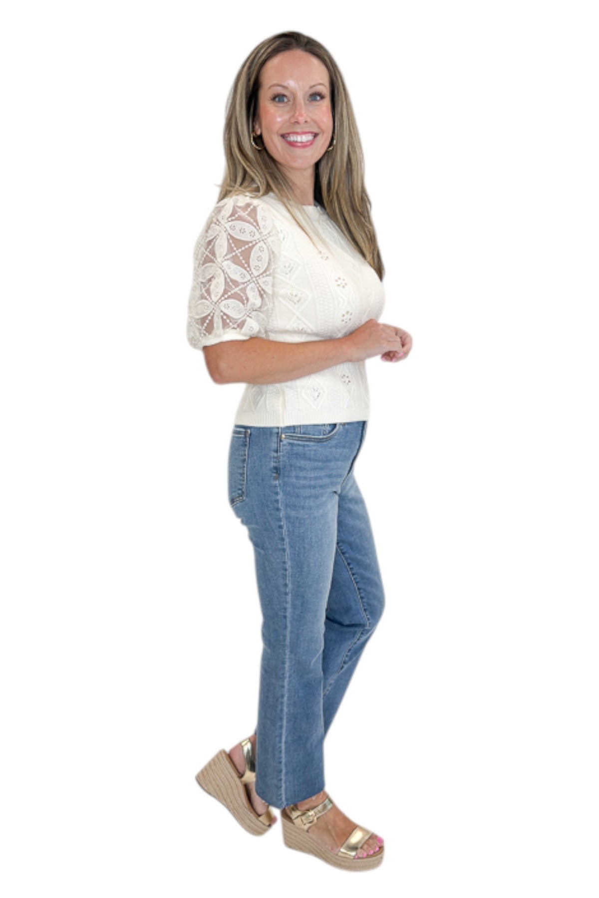 Side view of woman wearing Swagger Boutique’s Cream Sheer Sleeve Sweater with jeans against white studio background.