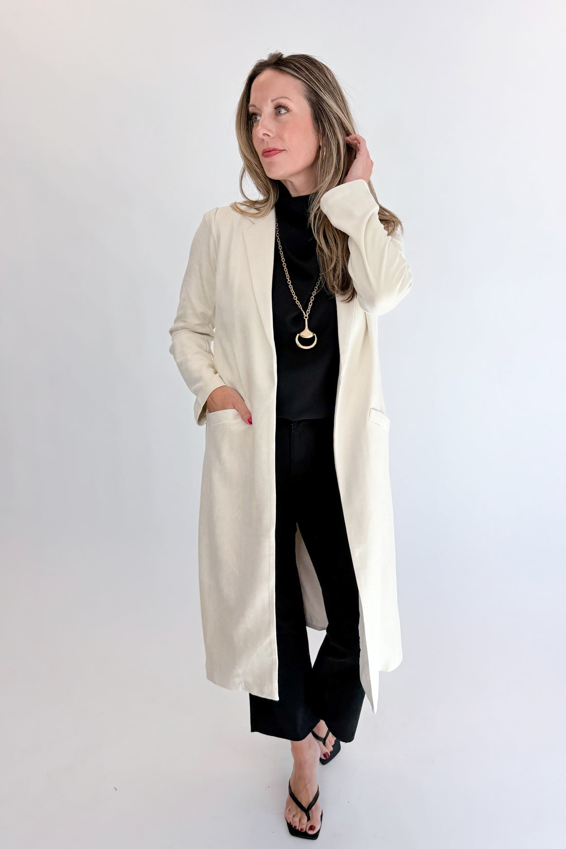Front view of woman wearing Swagger Boutique’s Cream Suede Duster Cardigan with jeans against white studio background.