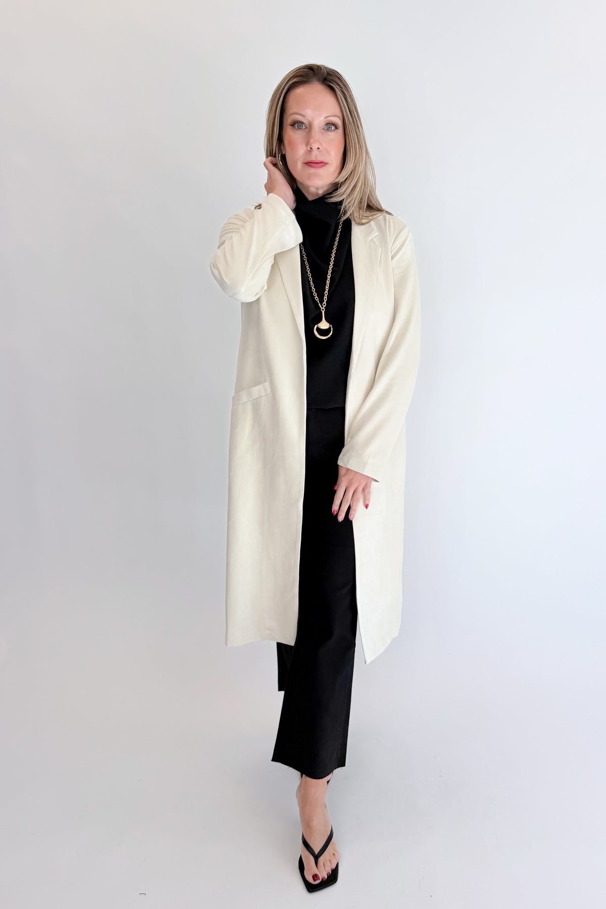 Front view of woman wearing Swagger Boutique’s Cream Suede Duster Cardigan with jeans against white studio background.