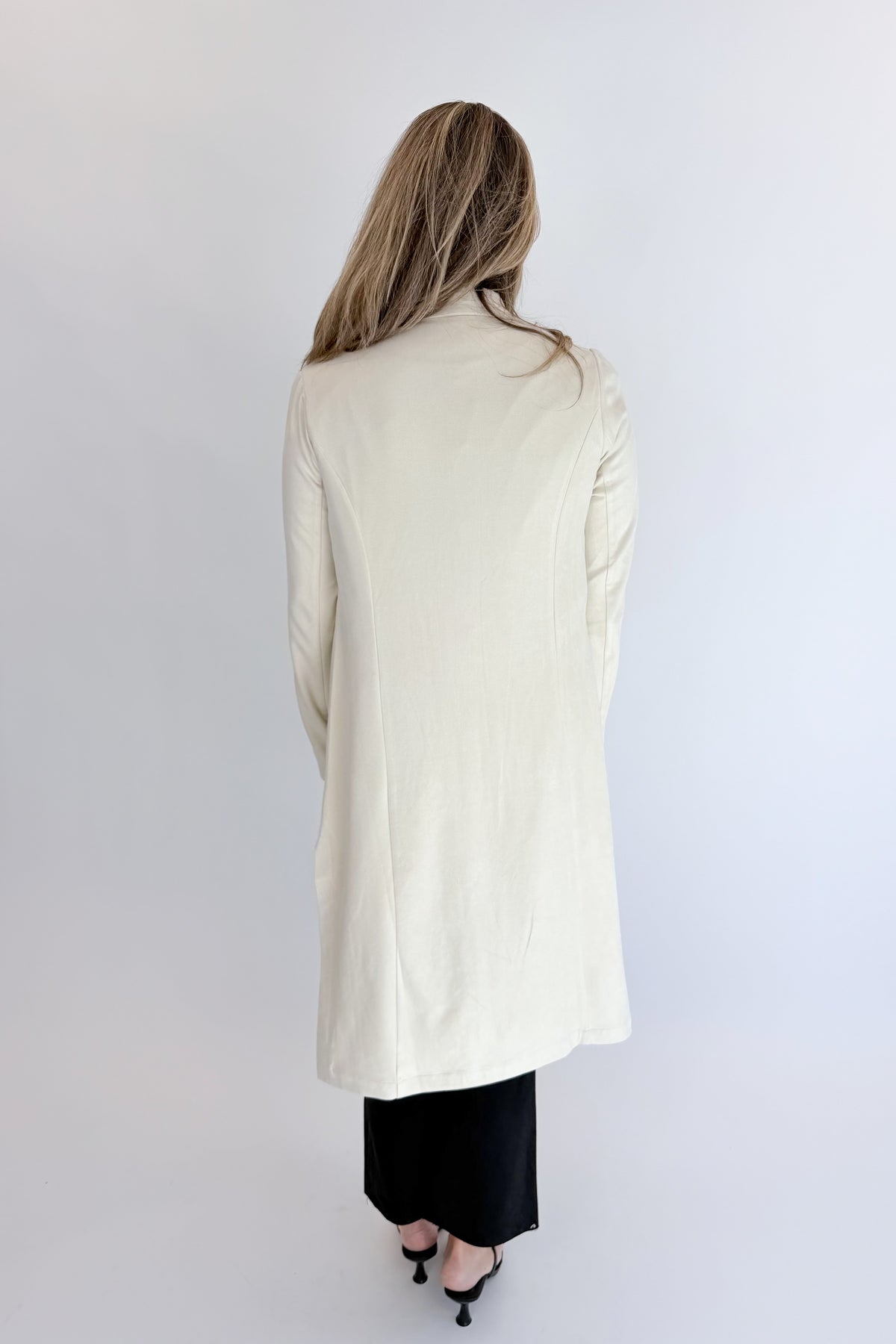 Back view of woman wearing Swagger Boutique’s Cream Suede Duster Cardigan with jeans against white studio background.