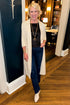Front view of woman wearing Swagger Boutique’s Cream Suede Duster Cardigan with jeans standing outside an office.