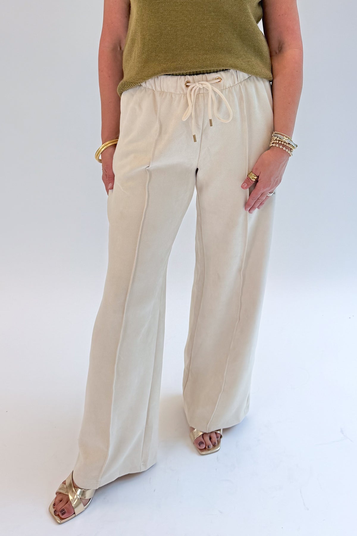 Front view of woman wearing Swagger Boutique’s Cream Suede Pants with sweater against white studio background.