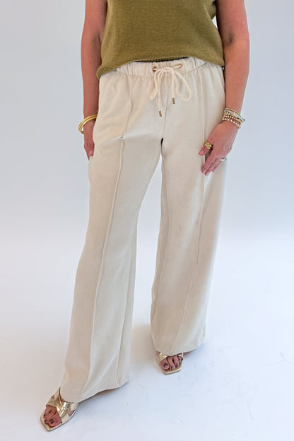 Front view of woman wearing Swagger Boutique’s Cream Suede Pants with sweater against white studio background.