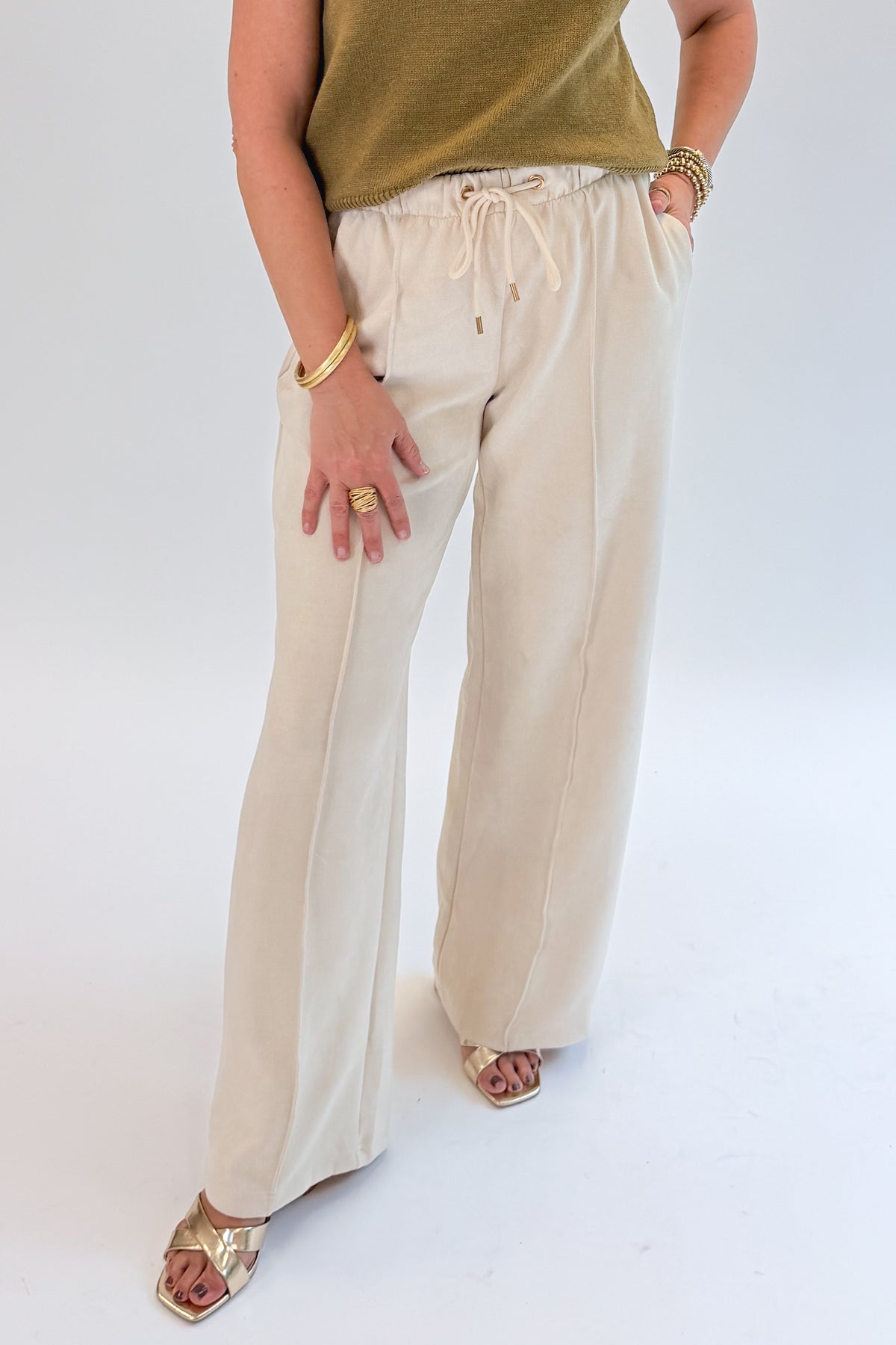 Front view of woman wearing Swagger Boutique’s Cream Suede Pants with sweater against white studio background.