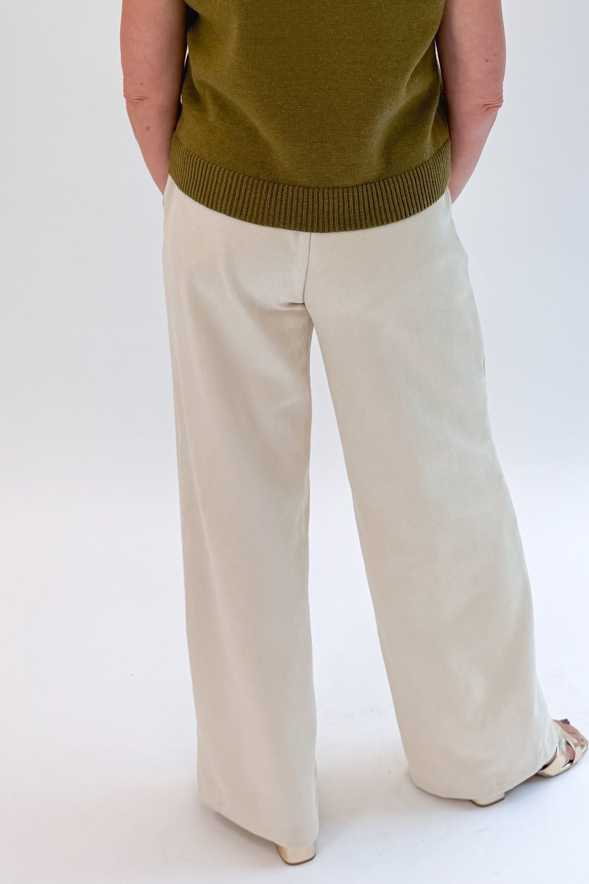 Back view of woman wearing Swagger Boutique’s Cream Suede Pants with sweater against white studio background.