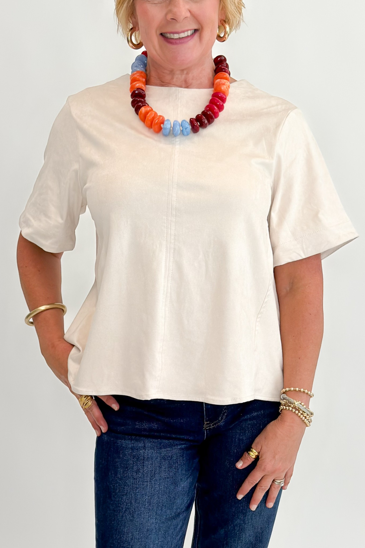 Front detail view of woman wearing Swagger Boutique’s Cream Suede Swing Top with jeans against white studio background.