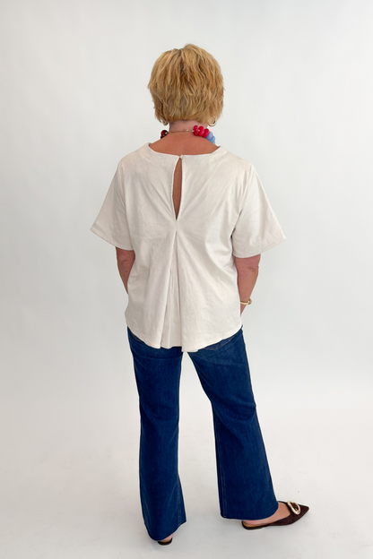 Back view of woman wearing Swagger Boutique’s Cream Suede Swing Top with jeans against white studio background.
