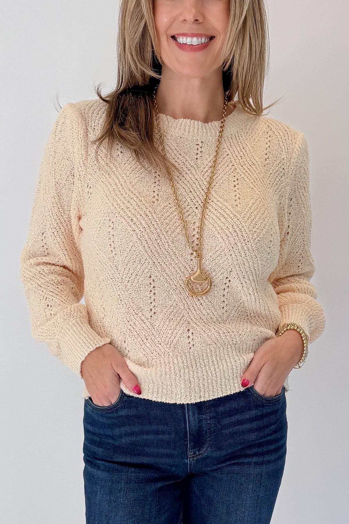 Front detail view of woman wearing Swagger Boutique’s Cream Textured Crew Neck Sweater with jeans against white studio background.