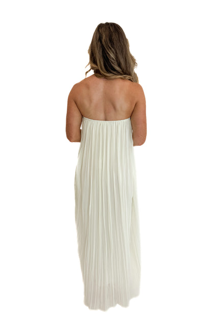 Back view of woman wearing Swagger Boutique’s Cream With Large Floral Print Pleat Detail Maxi Dress with sandals against white studio background.