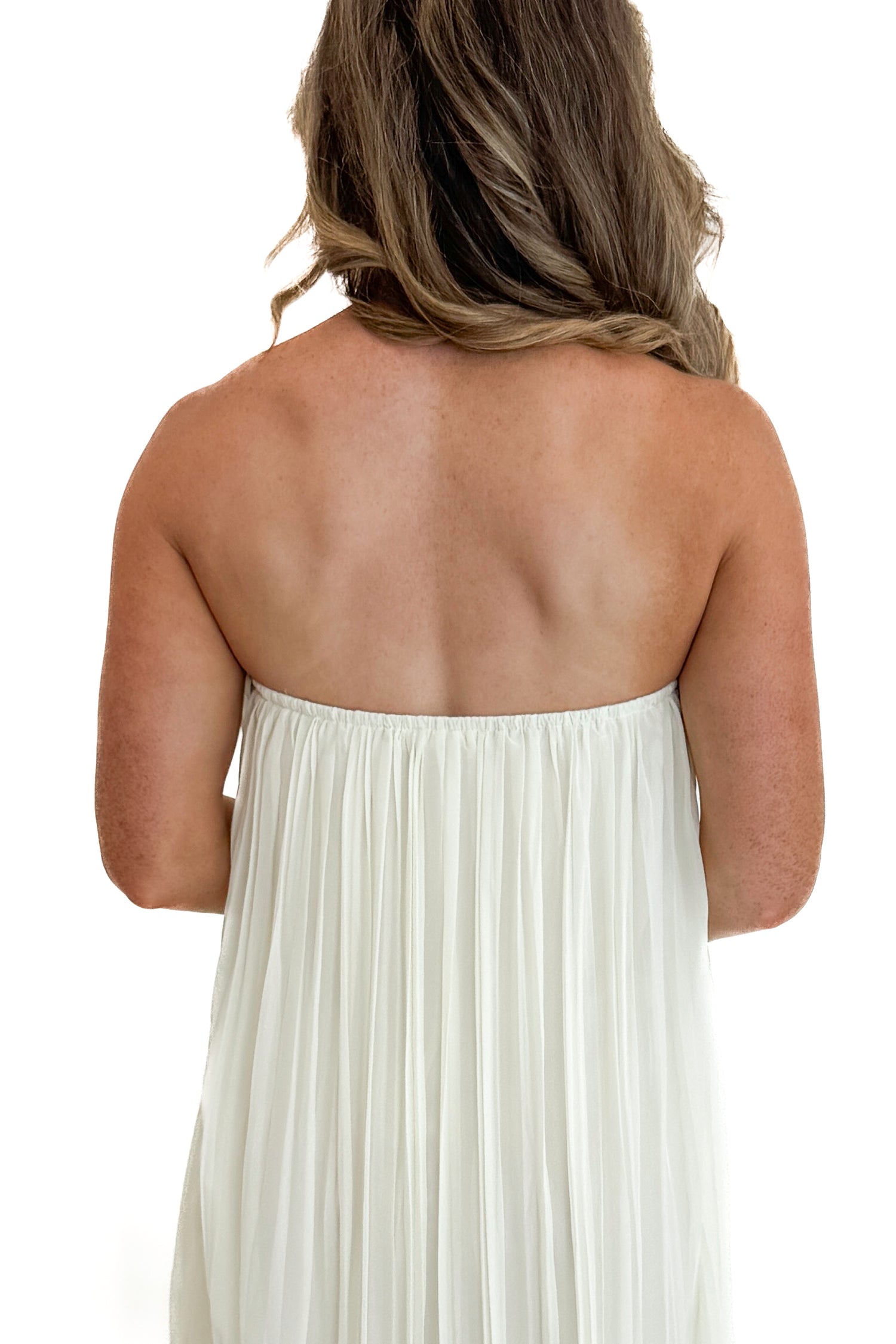 Back detail view of woman wearing Swagger Boutique’s Cream With Large Floral Print Pleat Detail Maxi Dress with sandals against white studio background.