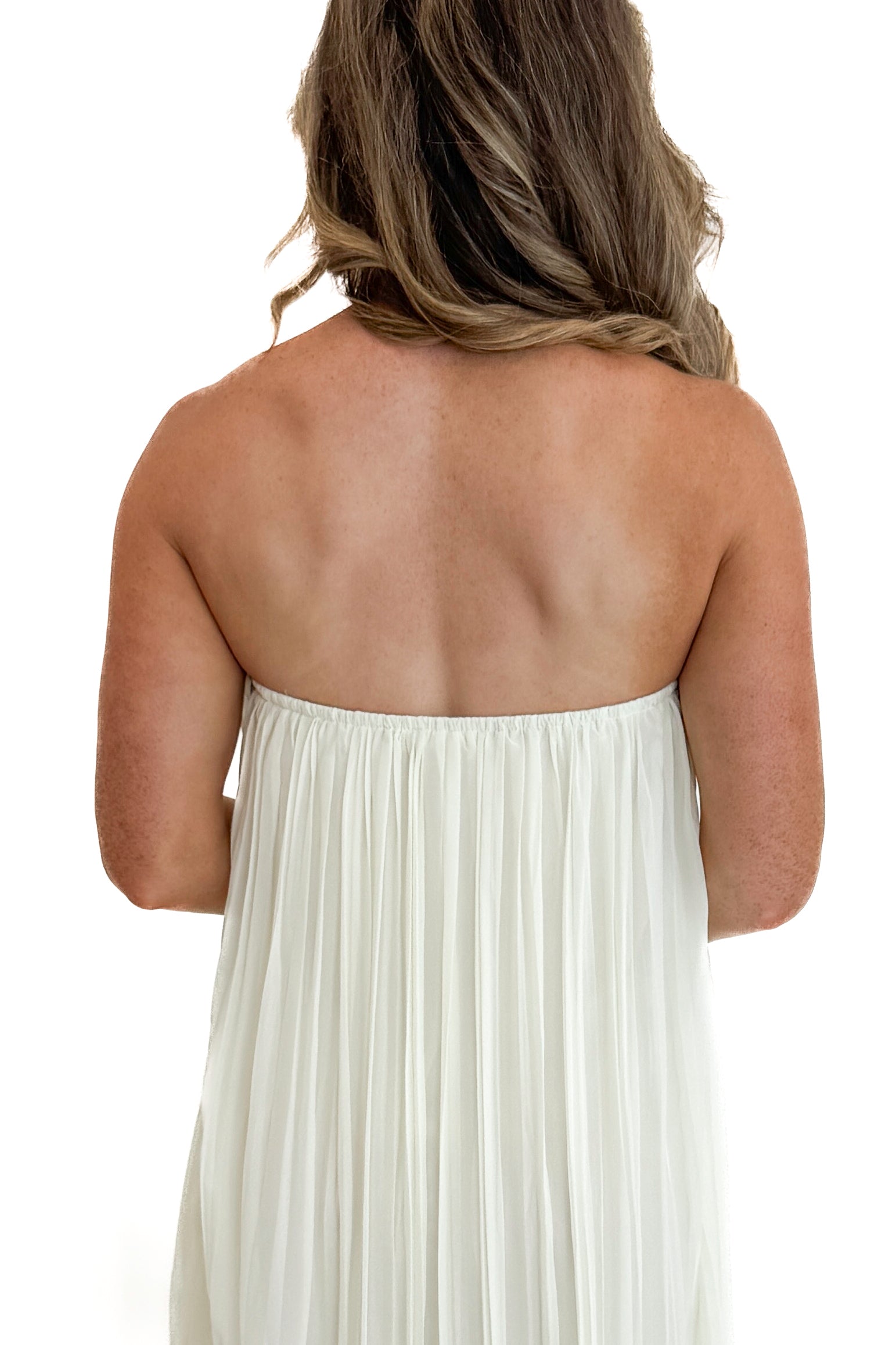 Back detail view of woman wearing Swagger Boutique’s Cream With Large Floral Print Pleat Detail Maxi Dress with sandals against white studio background.