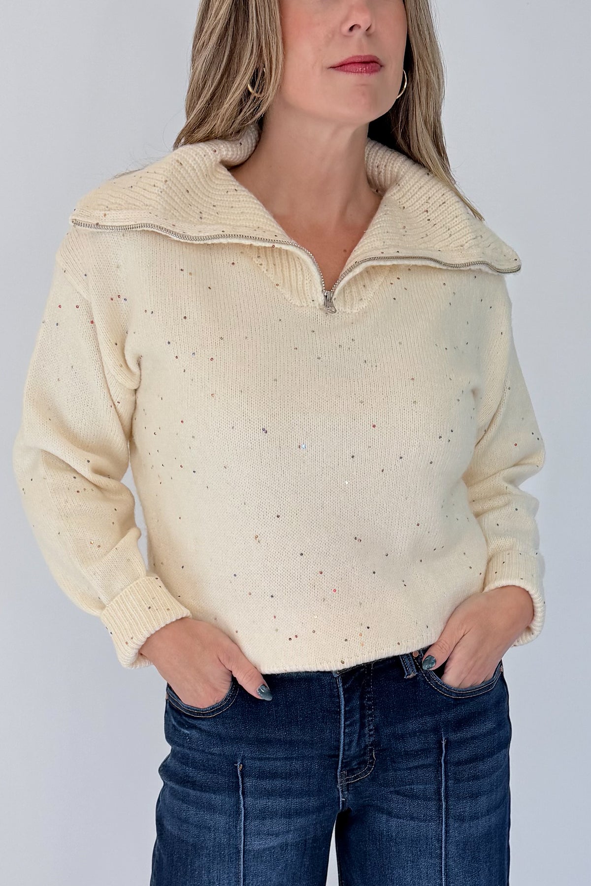 Front detail view of woman wearing Swagger Boutique’s Cream With Multi Sequins Sweater with jeans against white studio background.