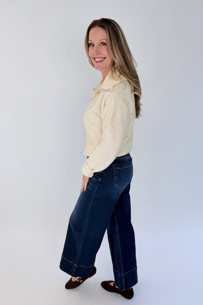 Side view of woman wearing Swagger Boutique’s Cream With Multi Sequins Sweater with jeans against white studio background.