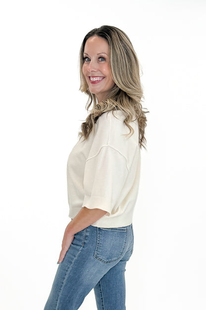 Side view of woman wearing Swagger Boutique’s Cream 3/4 Sleeve Lightweight Sweater by Entro with jeans against white studio background.
