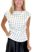 Front detail view of woman wearing Swagger Boutique’s Cream & Black Polka Dot Boat Neck Tank with Black Satin Mini Skirt against white studio background.