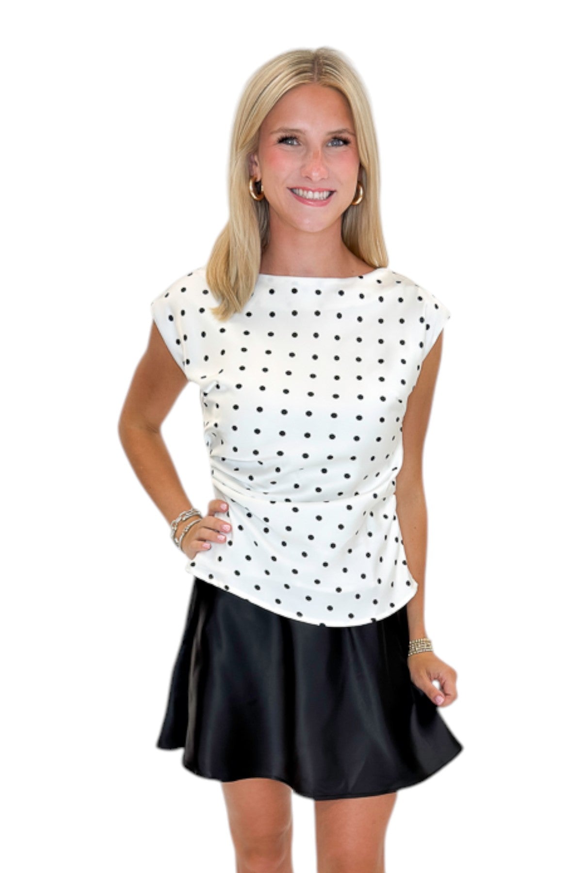 Front view of woman wearing Swagger Boutique’s Cream &amp; Black Polka Dot Boat Neck Tank with Black Satin Mini Skirt against white studio background.