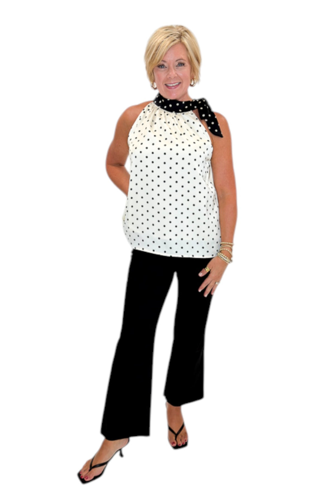 Front view of woman wearing Swagger Boutique’s Cream &amp; Black Polka Dot Halter Neck Tank with jeans against white studio background.