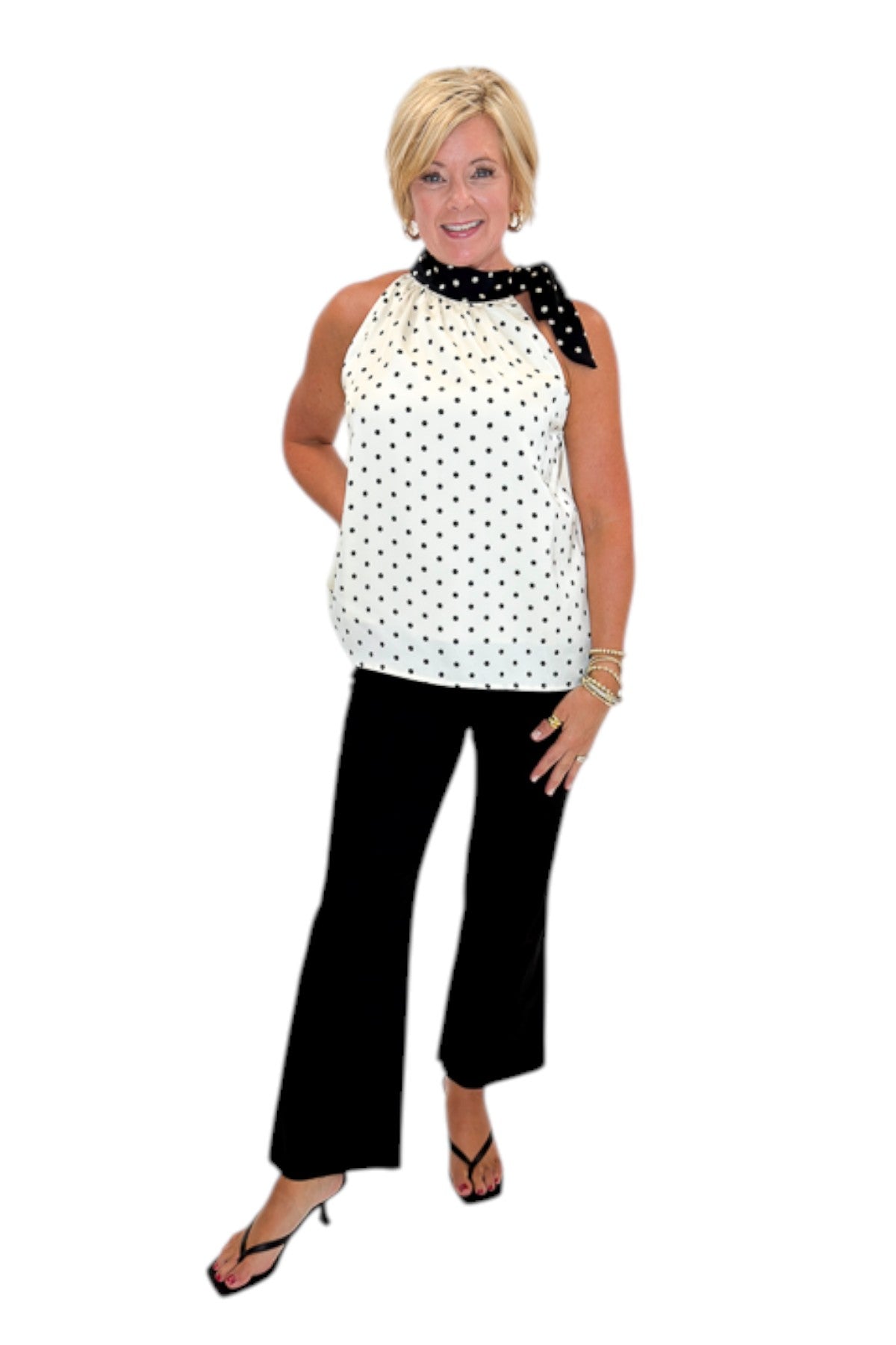 Front view of woman wearing Swagger Boutique’s Cream &amp; Black Polka Dot Halter Neck Tank with jeans against white studio background.