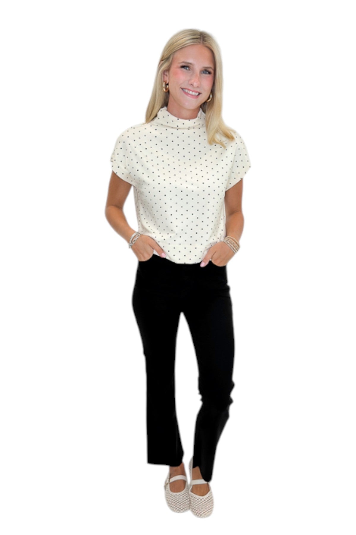 Front view of woman wearing Swagger Boutique’s Cream &amp; Black Polka Dot Mock Neck Top by Entro with jeans against white studio background.