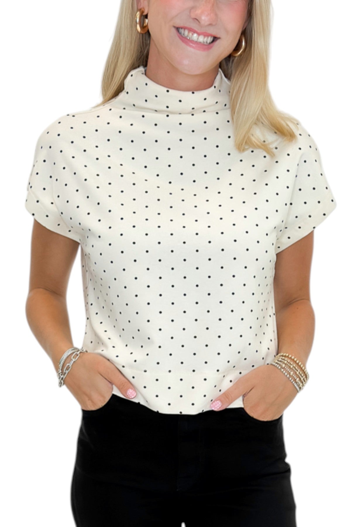 Front detail view of woman wearing Swagger Boutique’s Cream &amp; Black Polka Dot Mock Neck Top by Entro with jeans against white studio background.