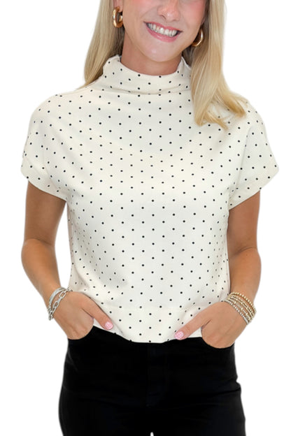 Front detail view of woman wearing Swagger Boutique’s Cream &amp; Black Polka Dot Mock Neck Top by Entro with jeans against white studio background.