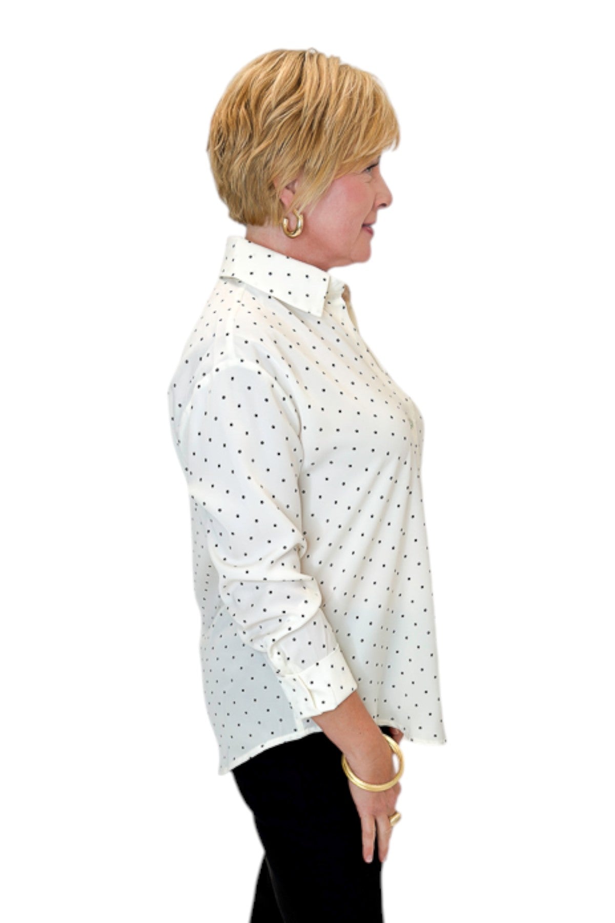 Side view of woman wearing Swagger Boutique’s Cream &amp; Black Polka Dot Satin Button Up Top with jeans against white studio background.