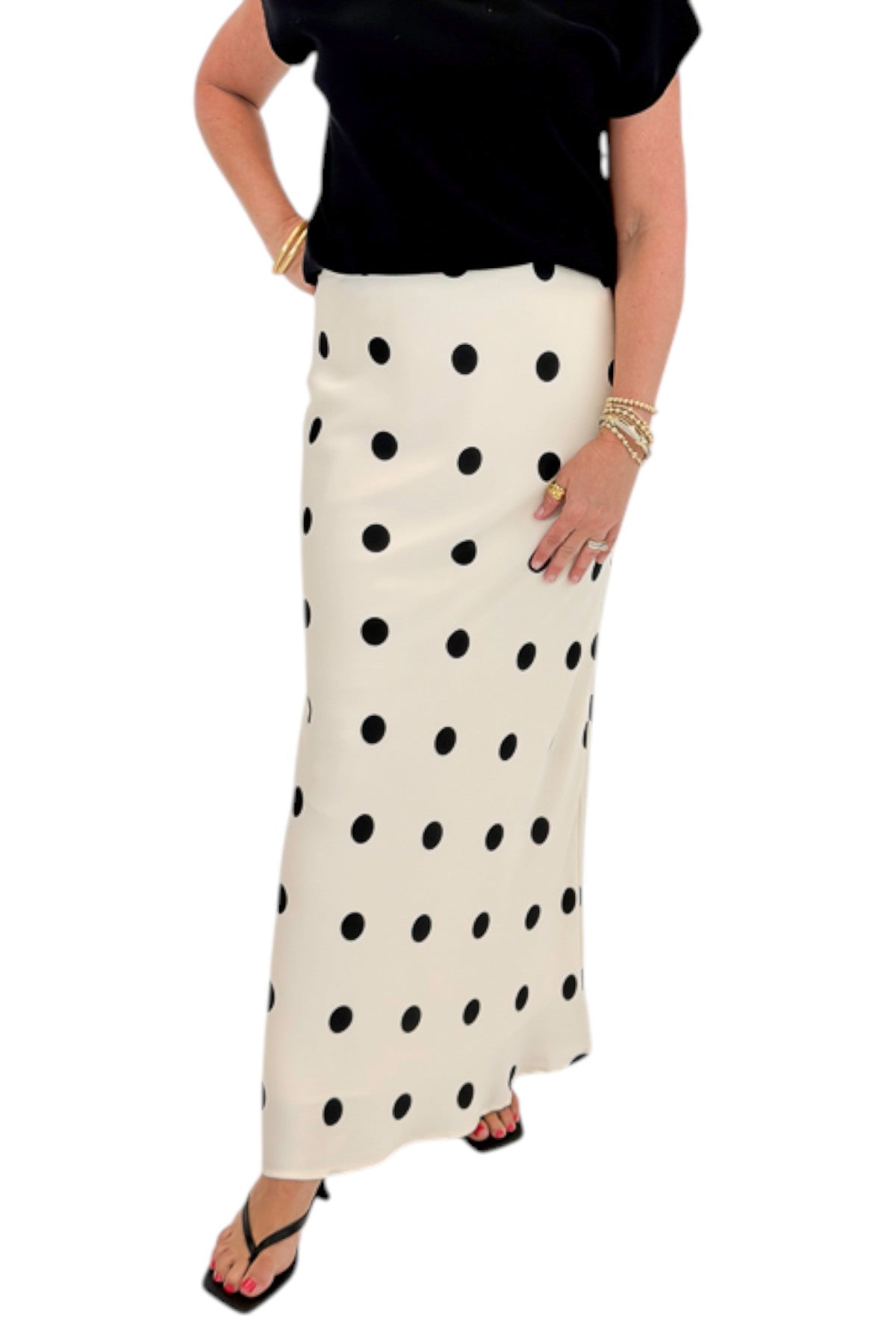 Front detail view of woman wearing Swagger Boutique’s Black Shirred Cap Sleeve Sweater with Cream &amp; Black Polka Dot Satin Skirt against white studio background.