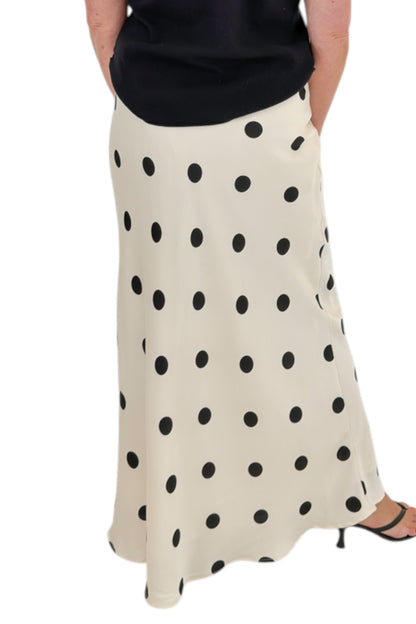 Back detail view of woman wearing Swagger Boutique’s Black Shirred Cap Sleeve Sweater with Cream &amp; Black Polka Dot Satin Skirt against white studio background.