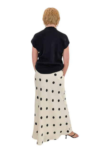 Back view of woman wearing Swagger Boutique’s Black Shirred Cap Sleeve Sweater with Cream &amp; Black Polka Dot Satin Skirt against white studio background.