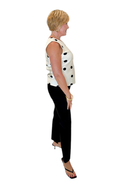 Side view of woman wearing Swagger Boutique’s Cream &amp; Black Polka Dot Satin Tank with jeans against white studio background.