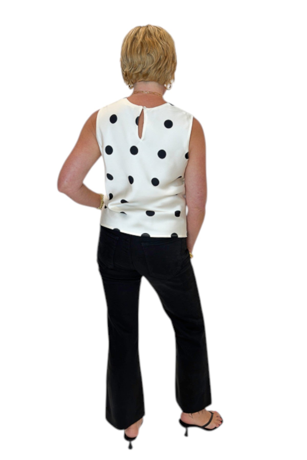 Back view of woman wearing Swagger Boutique’s Cream &amp; Black Polka Dot Satin Tank with jeans against white studio background.