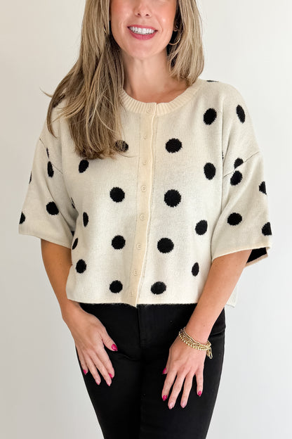 Front detail view of woman wearing Swagger Boutique’s Cream &amp; Black Polka Dot Short Sleeve Cardigan with jeans against white studio background.