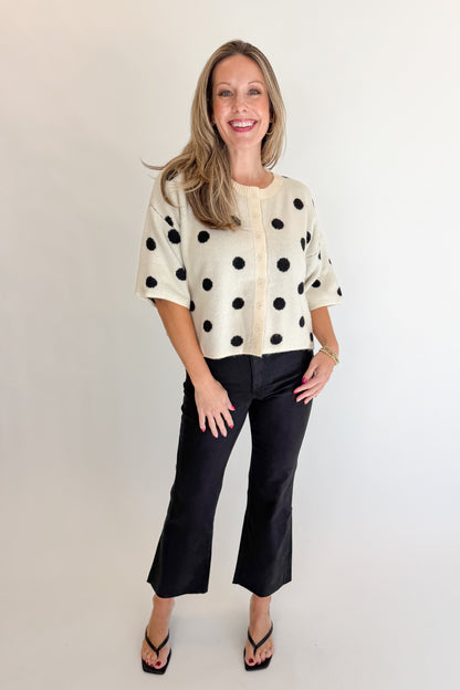Front view of woman wearing Swagger Boutique’s Cream &amp; Black Polka Dot Short Sleeve Cardigan with jeans against white studio background.
