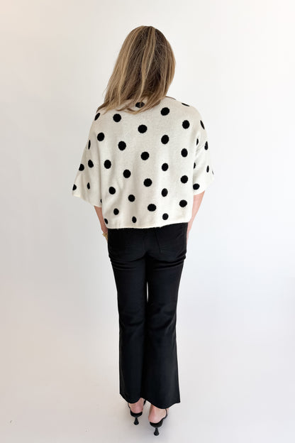 Back view of woman wearing Swagger Boutique’s Cream &amp; Black Polka Dot Short Sleeve Cardigan with jeans against white studio background.