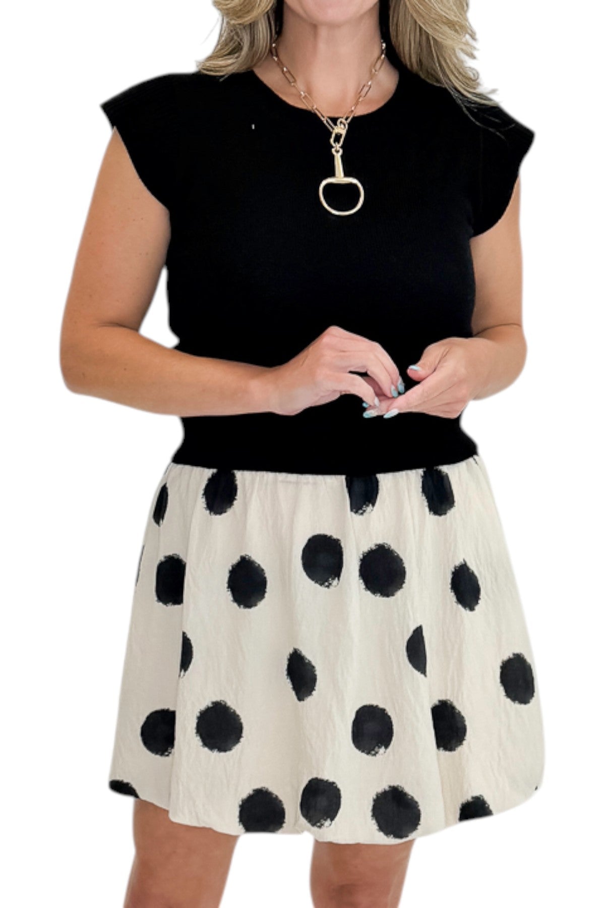 Front detail view of woman wearing Swagger Boutique’s Cream &amp; Black Polka Dot Skirt by THML with black sweater against white studio background.