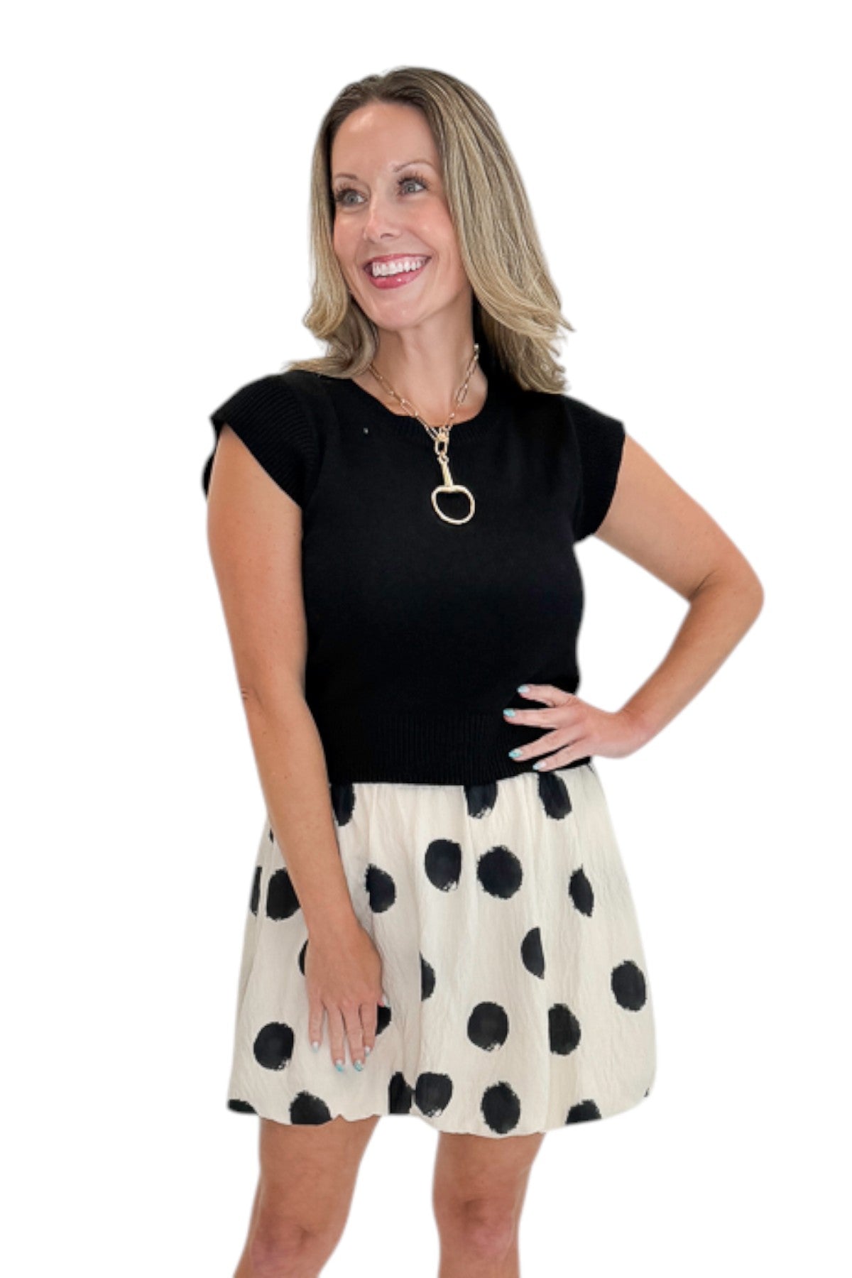 Front view of woman wearing Swagger Boutique’s Cream &amp; Black Polka Dot Skirt by THML with black sweater against white studio background.
