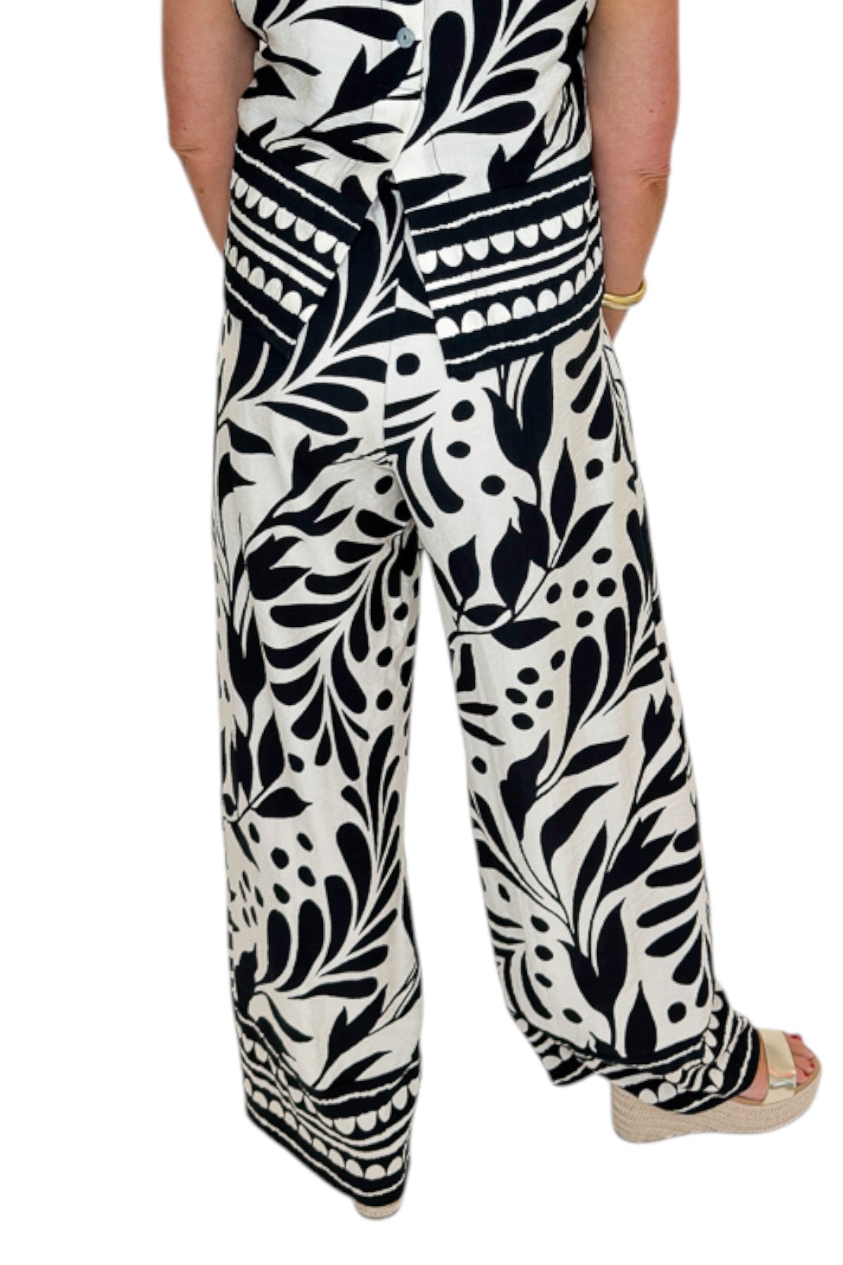 Back view of woman wearing Swagger Boutique’s Cream &amp; Black Printed Tank &amp; Wide Leg Pants against white studio background.