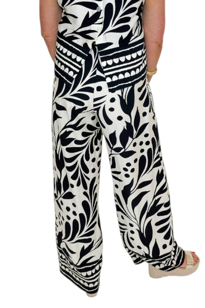 Back view of woman wearing Swagger Boutique’s Cream &amp; Black Printed Tank &amp; Wide Leg Pants against white studio background.
