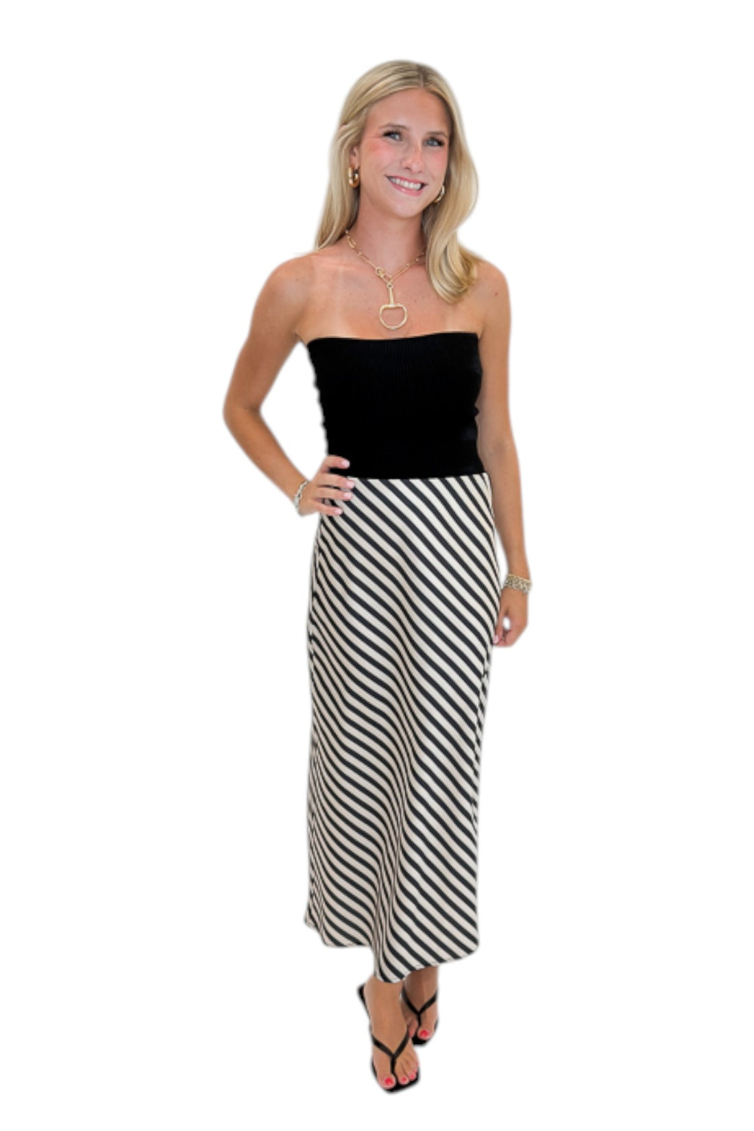 Front view of woman wearing Swagger Boutique’s Cream &amp; Black Striped Satin Midi Skirt with black top against white studio background.