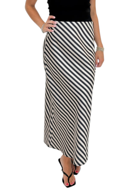 Front detail view of woman wearing Swagger Boutique’s Cream &amp; Black Striped Satin Midi Skirt with black top against white studio background.