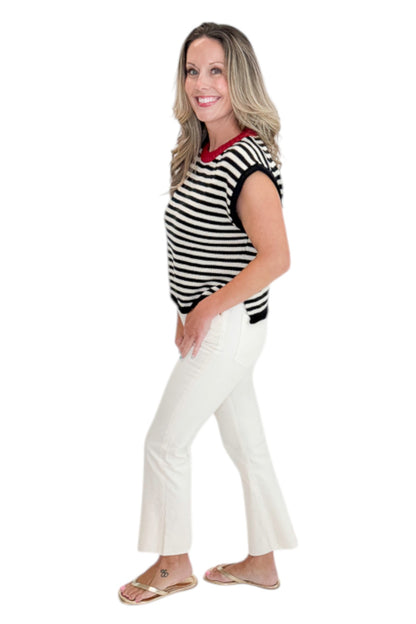 Side view of woman wearing Swagger Boutique’s Cream &amp; Black Striped Sleeveless Sweater with jeans against white studio background.