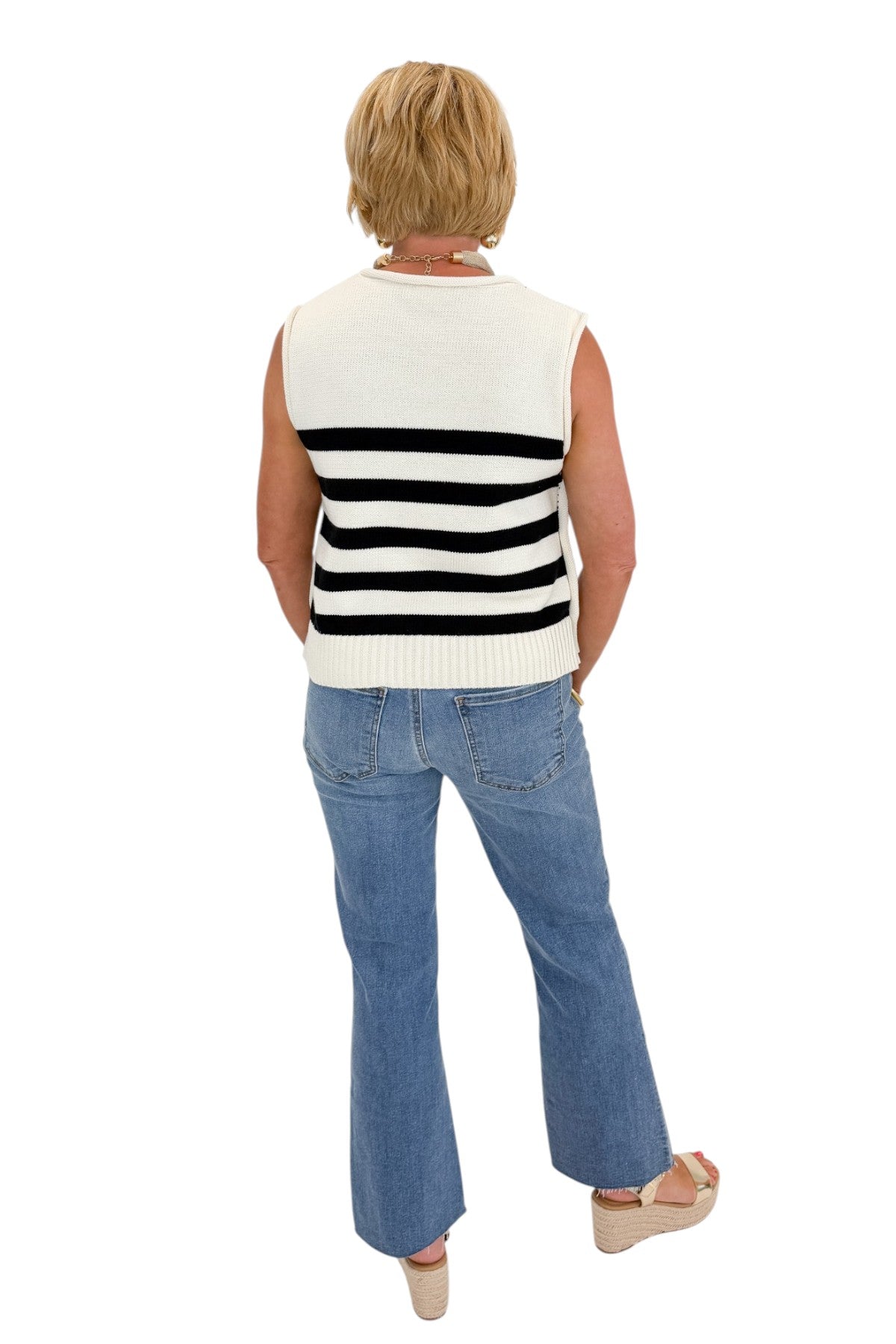 back view of woman wearing cap sleeve white and black striped knit sweater. 