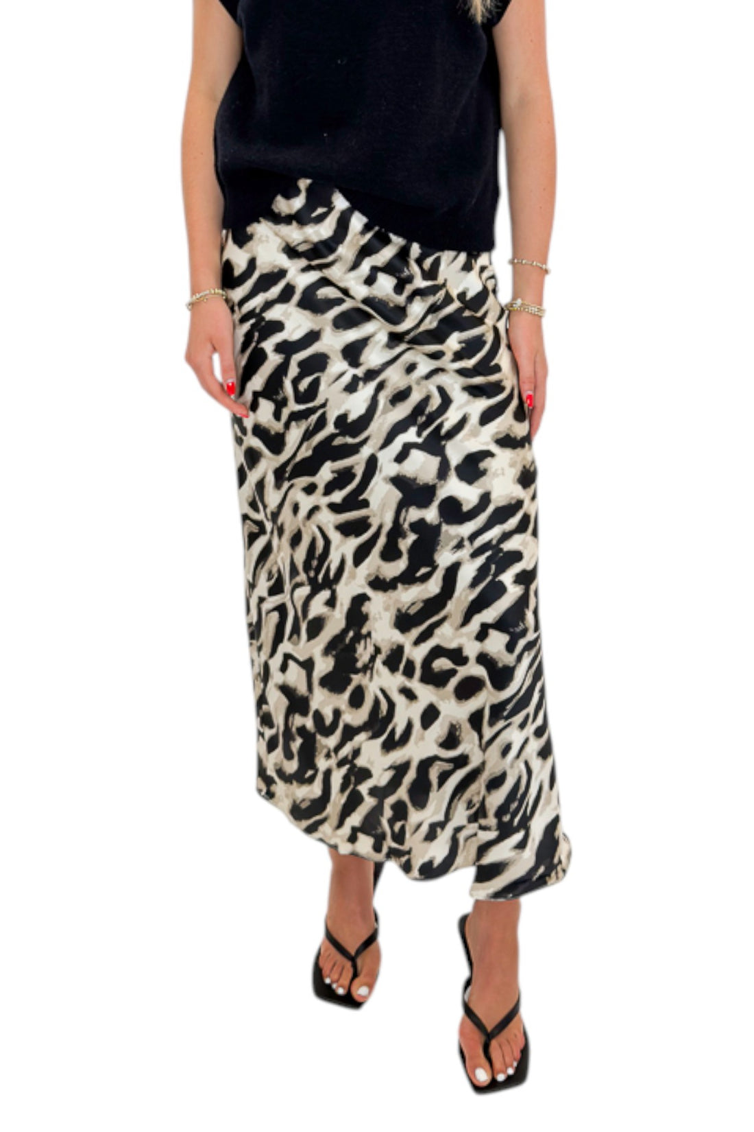 Front detail view of woman wearing Swagger Boutique’s Black Sleeveless Sweater by Entro with Cream &amp; Black Leopard Satin Midi Skirt against white studio background.