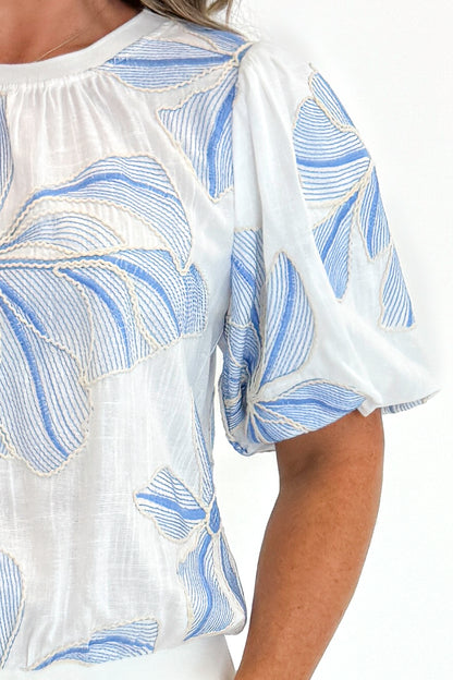 Front detail view of woman wearing Swagger Boutique’s Cream &amp; Blue Floral Embroidered Top against white studio background.
