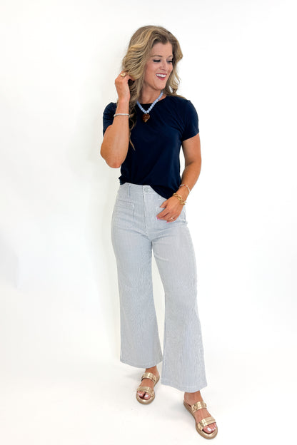 Front view of woman wearing Swagger Boutique’s Cream &amp; Blue Striped Jeans With Patch Pocket by Just Black Denim with blue Z Supply top against white studio background.