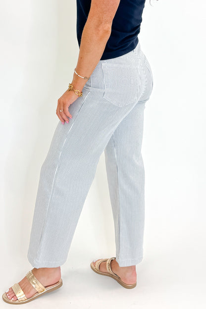 Side detail view of woman wearing Swagger Boutique’s Cream &amp; Blue Striped Jeans With Patch Pocket by Just Black Denim with blue Z Supply top against white studio background.